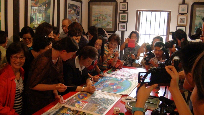 知名書法家詹秀蓉造訪位於金山的中國農民畫村，參觀者聚精會神地看著詹秀蓉揮毫留字